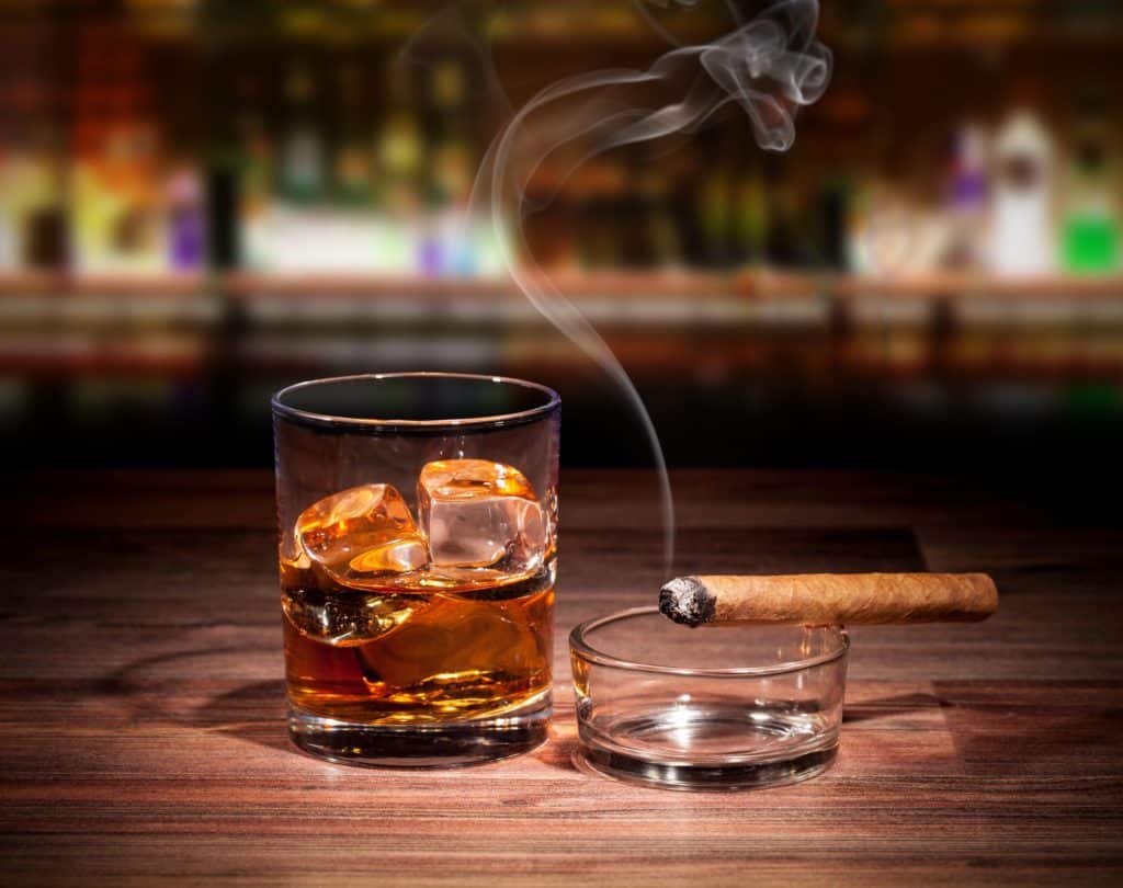 whiskey drink with smoking cigar on wooden table