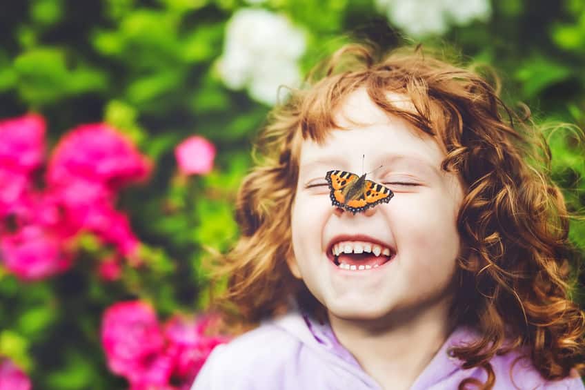 Laughing girl with a butterfly on her nose.